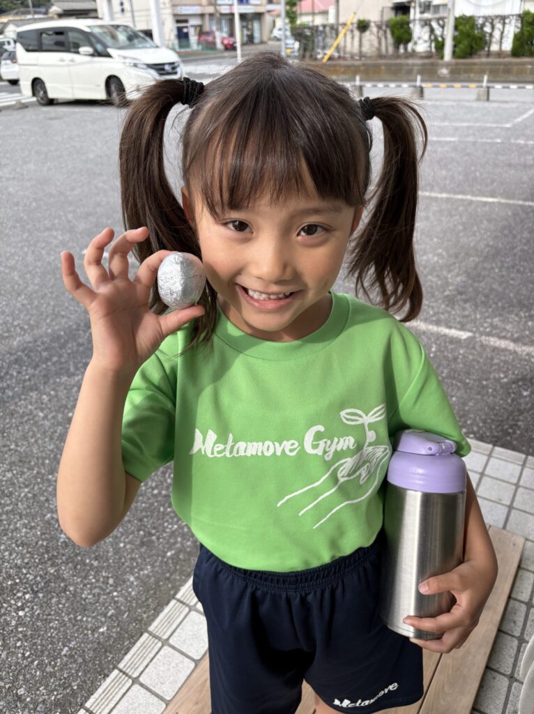 アルミ玉チャレンジで作成途中の作品を持つ女の子。継続力と集中力を育むMetamove Gymの特別ワーク。