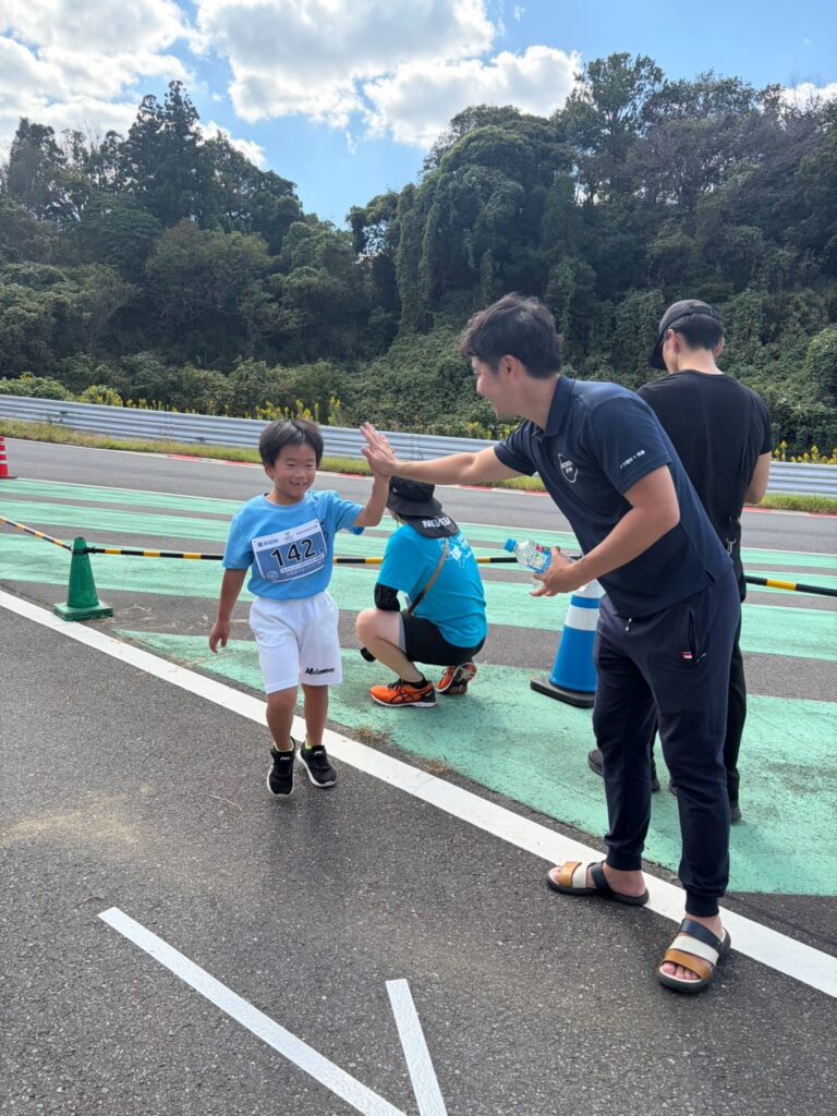 木更津ブルーベリーランで走る子どもとハイタッチするMetamove Gymの指導者